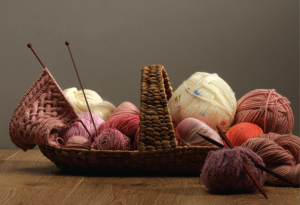 Image of balls of wool in a backet, with knitting needles