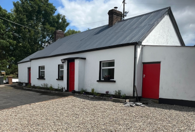 Image of exterior of cottage with white walls and red doors