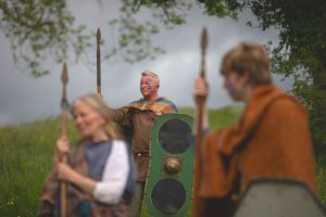 Image depicts Celtic Warriors in traditional dress holding spheres and one holding a shield.