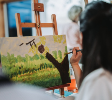 Person painting a landscape scene on a canvas set on an easel.