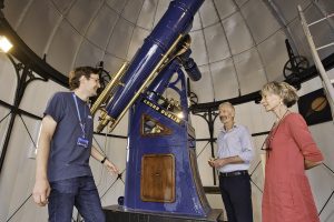 Telescope Tour at Armagh Observatory. Guide talking to visitors with telescope in background.