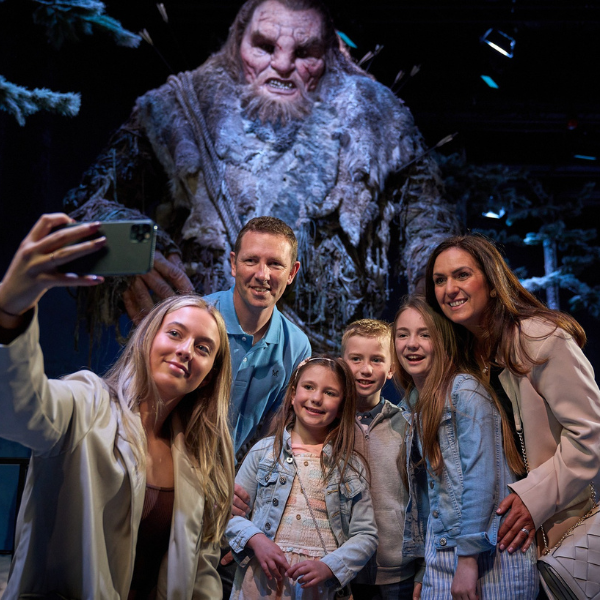 Group taking a selfie in front of a large creature display at the Game of Thrones Studio Tour.