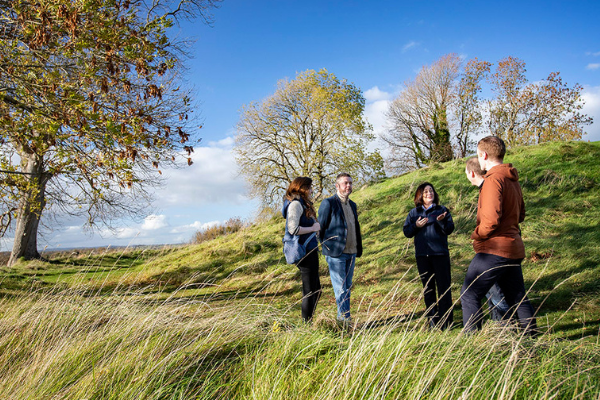 Group standing in tall grass at Navan Fort during a guided outdoor tour.