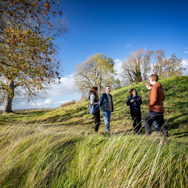 Group standing in tall grass at Navan Fort during a guided outdoor tour.