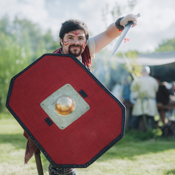 Costumed warrior holding a red shield and sword at Navan Centre & Fort.