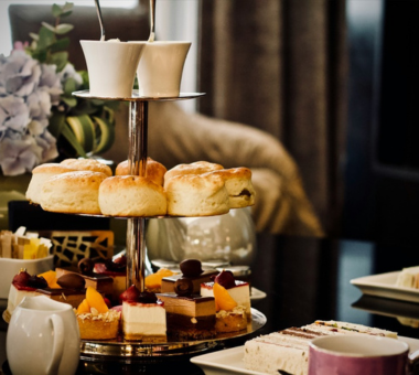 Tiered stand with scones, cakes, and desserts set for afternoon tea in an elegant indoor setting.