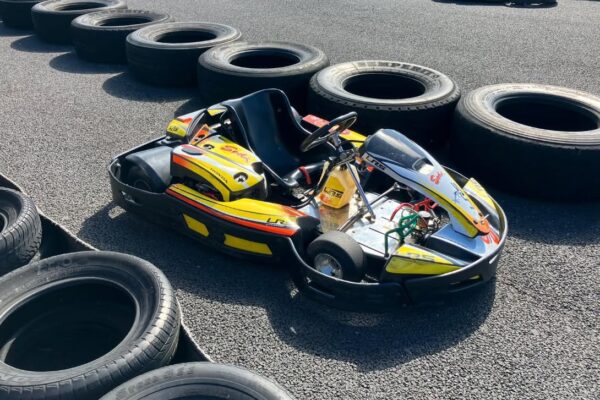 Go-kart parked beside a tyre-lined race track at Gosford Karting, with additional karts visible in the background.