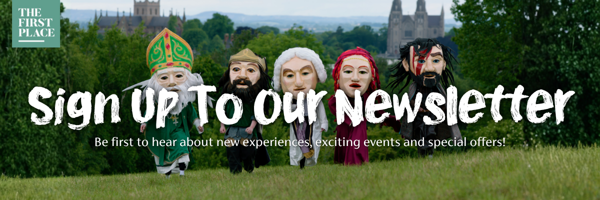 Promotional graphic inviting people to sign up to the Visit Armagh newsletter, featuring the Big Heads walking across a grassy hill in Armagh with both St Patrick’s cathedrals in the background and text about being first to hear about new experiences, events and special offers.