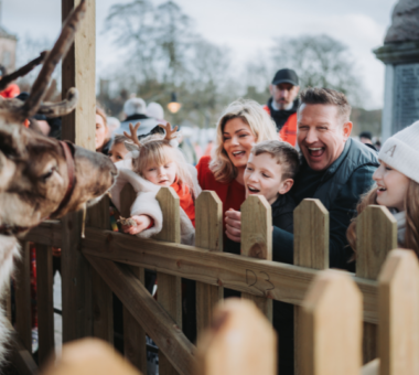 Children and adults meeting reindeer in a festive petting area during a family Christmas event at the Armagh Georgian Festival.