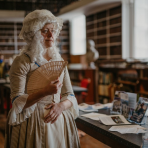 Person in Georgian period costume holding a folding fan during an event at Armagh Robinson Library as part of the Armagh Georgian Festival.