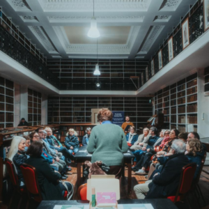 Audience attending the Rokeby Lecture at Armagh Robinson Library, seated among historic bookshelves while a speaker addresses the group.
