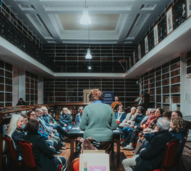 Audience attending the Rokeby Lecture at Armagh Robinson Library, seated among historic bookshelves while a speaker addresses the group.
